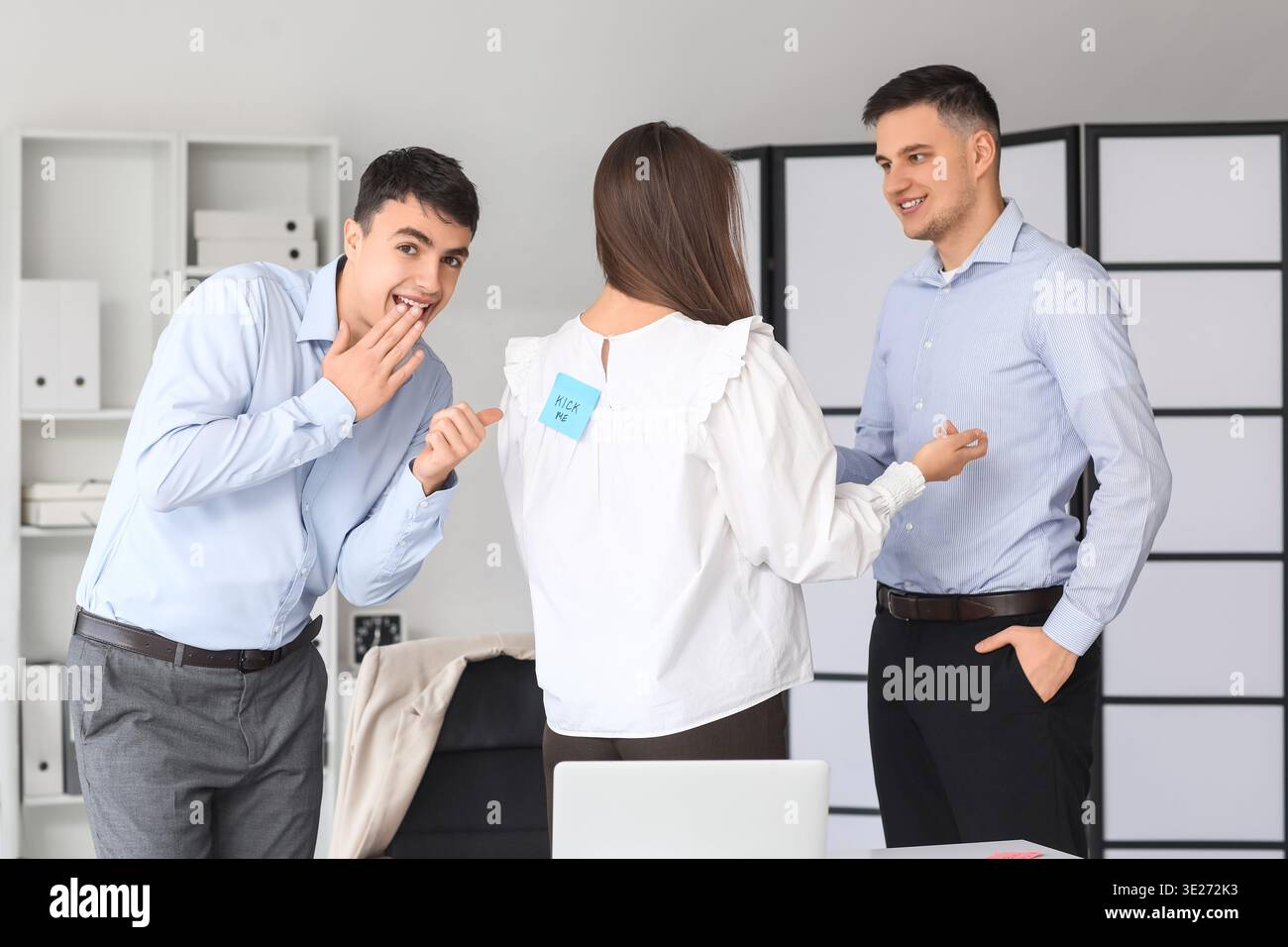 I giovani uomini e la loro collega con la carta adesiva sul suo ritorno in ufficio. Festa del Fool's Day di aprile Foto Stock
