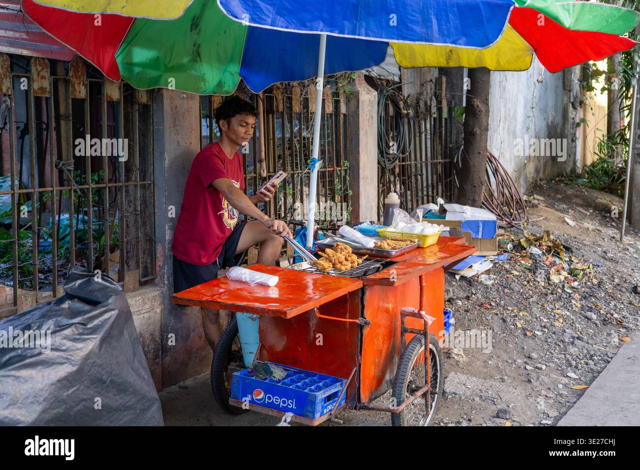 Venditore ambulante che vende pollo fritto da un carrello mobile nella città di Cebu, Filippine, mostrando economia informale, cultura del cibo di strada e vita urbana quotidiana Foto Stock