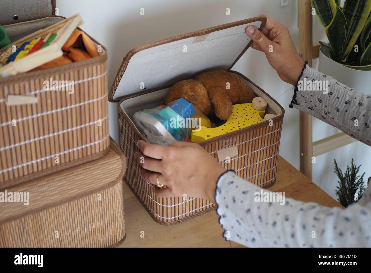 Organizzare i giocattoli in un contenitore su un tavolo di legno Foto Stock