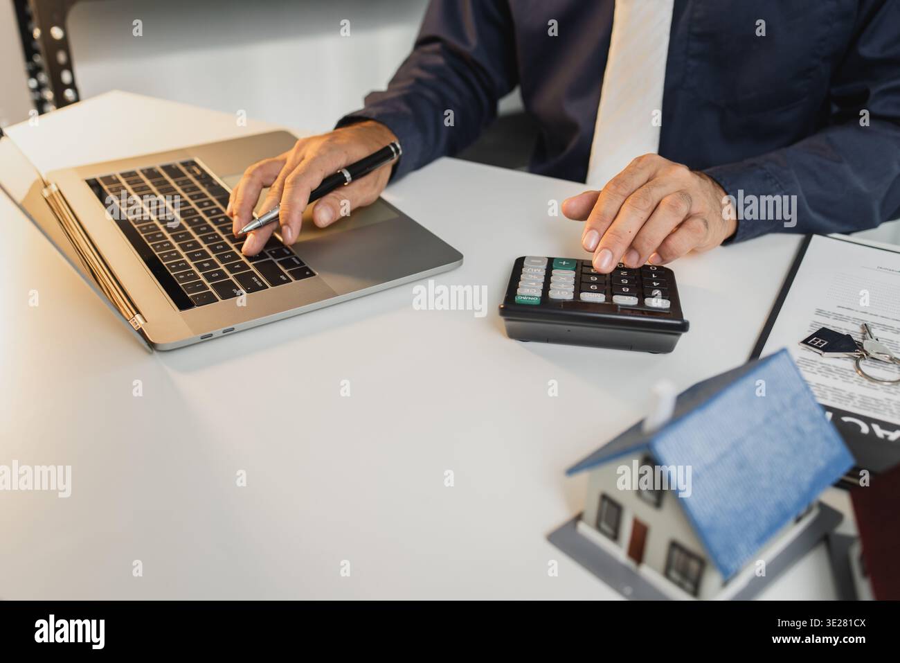 I documenti contrattuali, i modelli di casa, le chiavi e la calcolatrice sulla scrivania simboleggiano l'approvazione dei mutui ipotecari, il finanziamento immobiliare, la pianificazione degli investimenti e il decision-ma Foto Stock