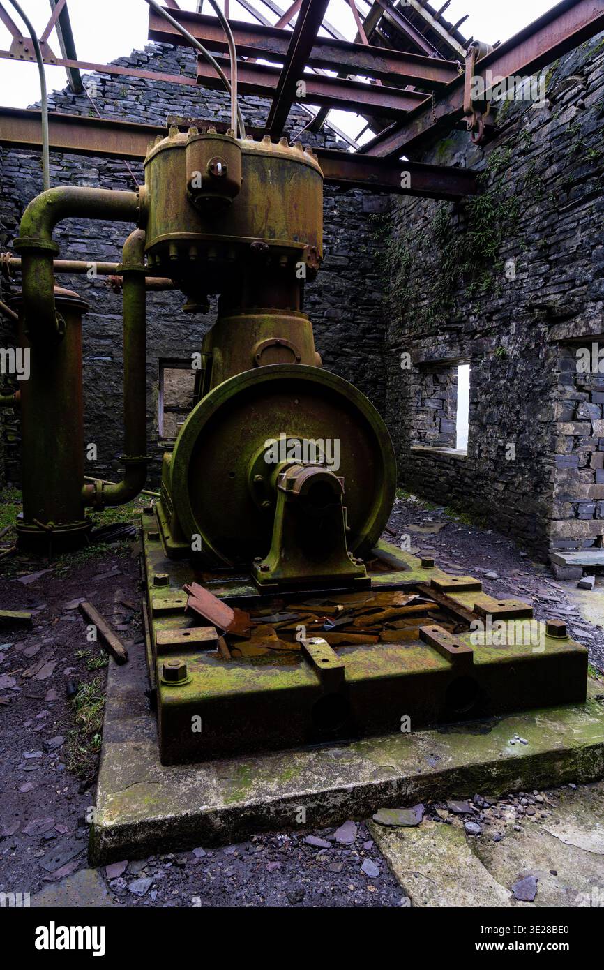 Vista grandangolare di un compressore d'aria coperto di muschio all'interno di un'officina in rovina presso la cava di ardesia Dinorwic Foto Stock