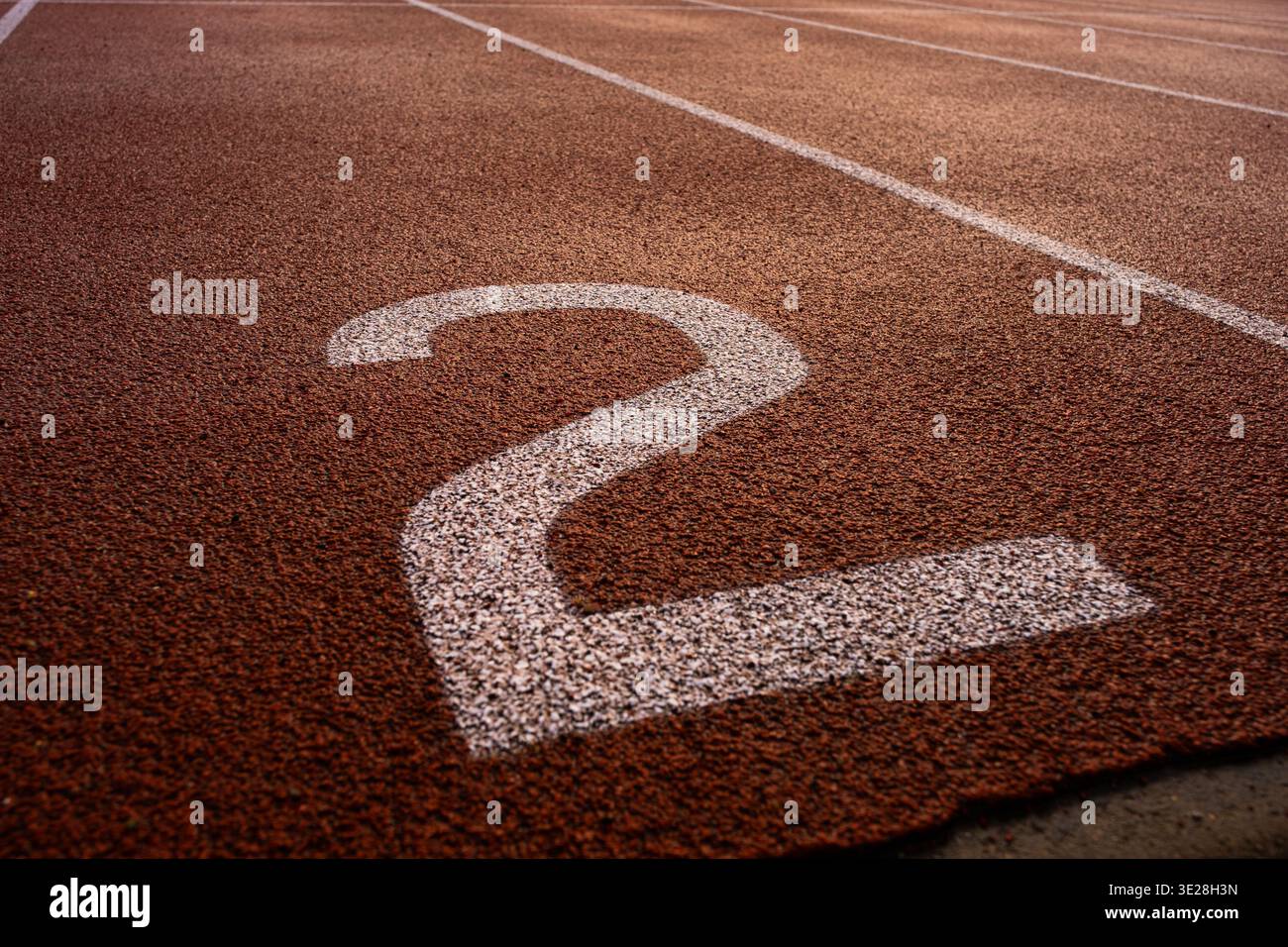 Primo piano del numero due dipinto su una pista da corsa sintetica rossa, linee di demarcazione su una pista di uno stadio di atletica Foto Stock