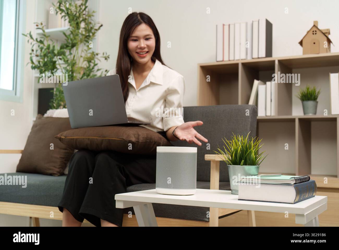 Interazione Smart Speaker. L'utente interagisce con l'altoparlante intelligente mentre lavora. Foto Stock