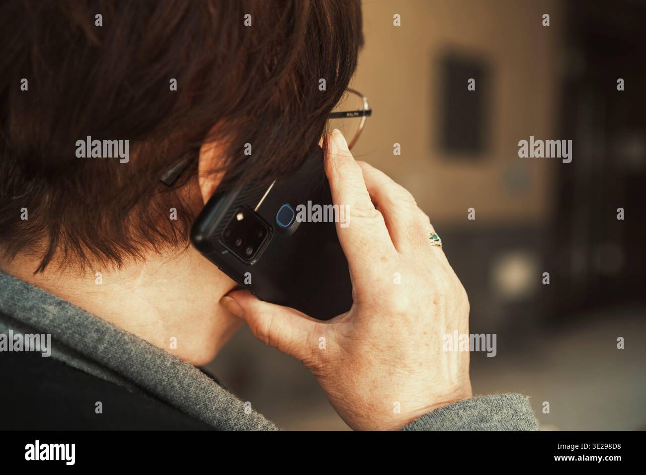 Donna anziana che parla su smartphone all'aperto, vista posteriore con spazio per le copie. Stile di vita attivo degli anziani e concetto di comunicazione mobile. Foto Stock