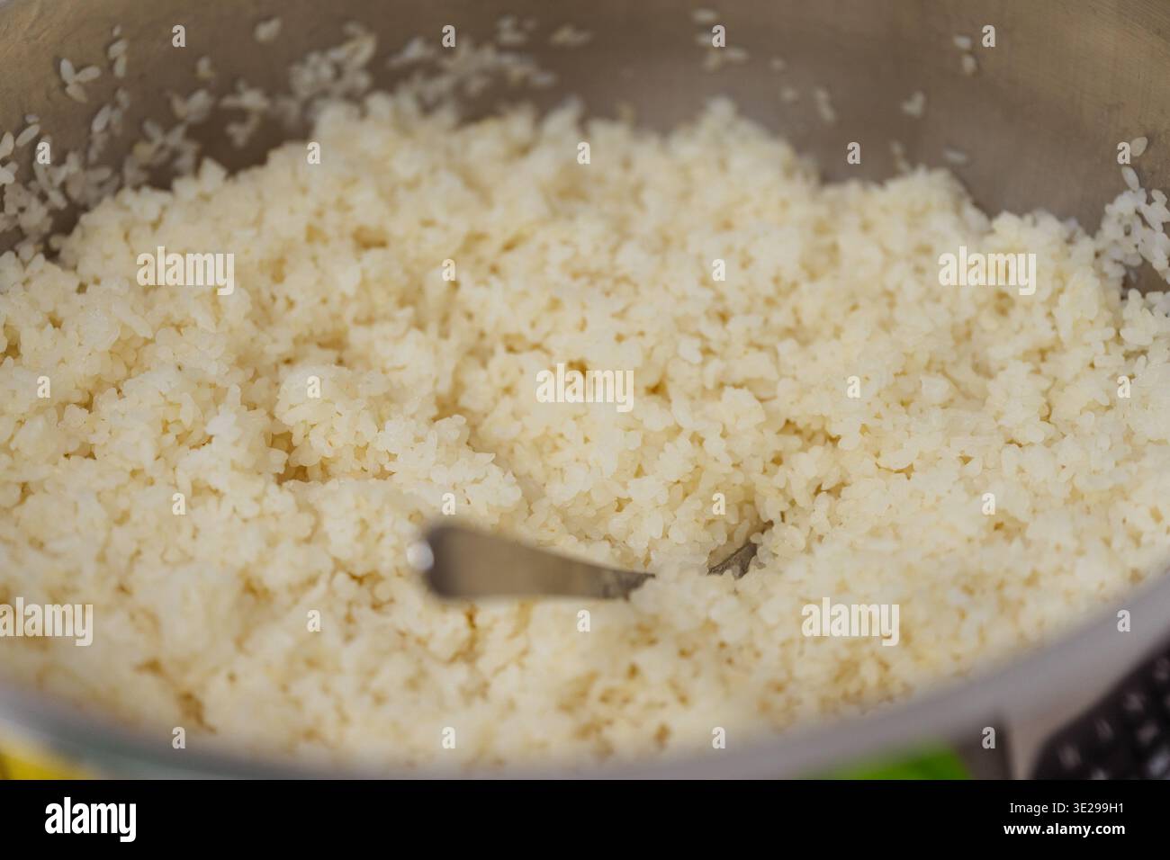 Primi piani di riso sushi nel recipiente di miscelazione, cereali glutinosi appiccicosi piegati con spatola, vapore caldo, sottile Foto Stock