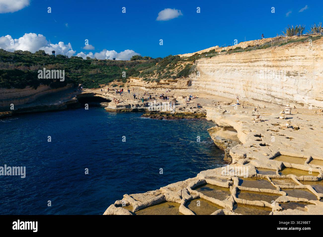 Vista aerea dell'aspra costa della piscina di San Pietro incontra il mare blu profondo, i bordi rocciosi contrastano con i bagnanti che si godono il sole invernale, Mar Foto Stock