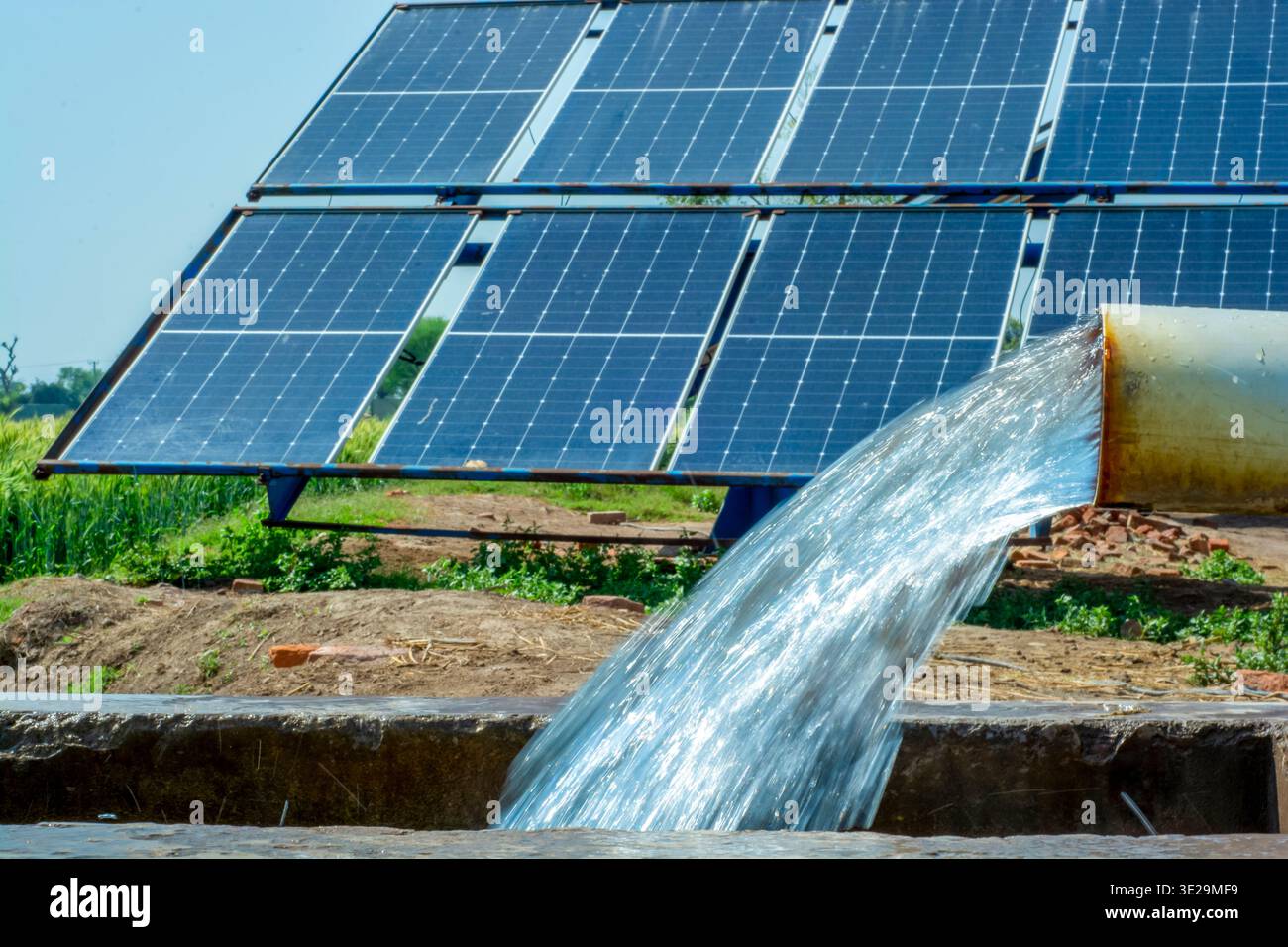 Un pozzo a tubo alimentato a energia solare che fornisce acqua per l'irrigazione in un vasto campo agricolo. Foto Stock