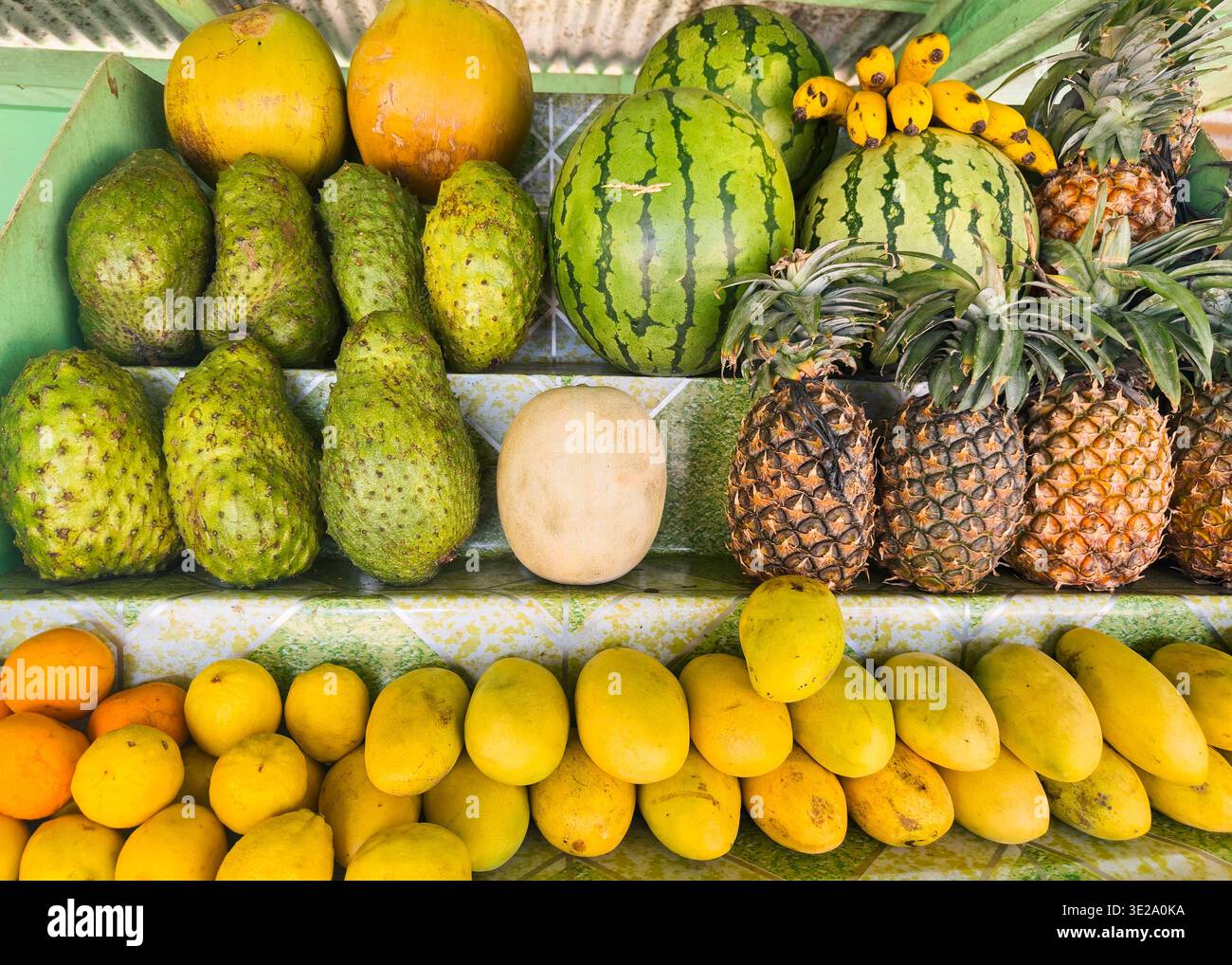 Frutta tropicale fresca in una bancarella di succhi di frutta nelle Filippine, tra cui mango, ananas, cocco e anguria. - Immagine stock catturata con smartphone
