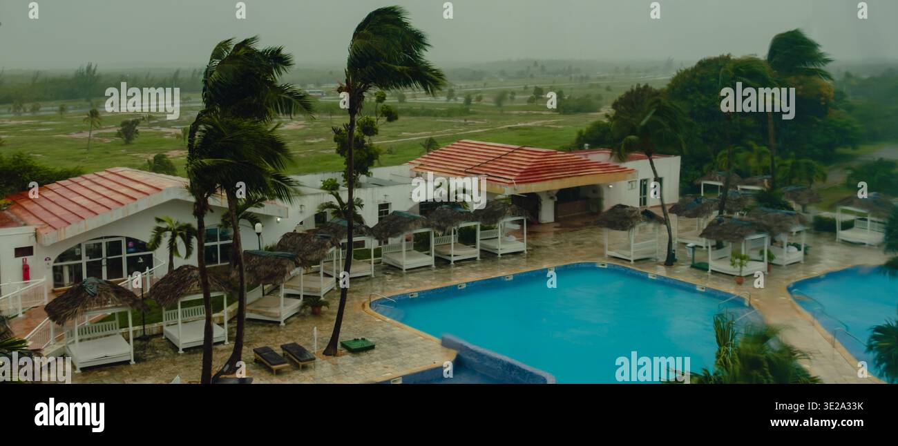 Tempesta, vento, pioggia fuori dalla finestra. Vista sulla piscina e sulle palme dell'hotel. Foto Stock