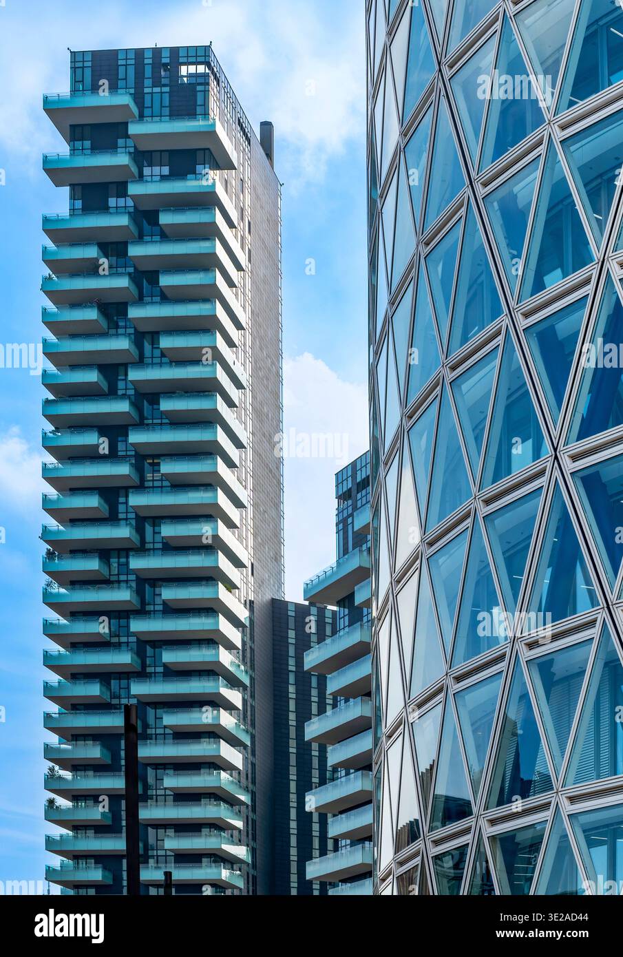 Milano, Lombardia, Italia - venerdì 13, 2026: Architettura moderna a Milano con balconi e una suggestiva facciata triangolare in vetro su un cielo blu Foto Stock