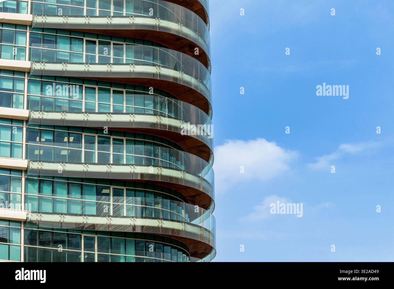 Milano, Lombardia, Italia - venerdì 13 2026: Elegante facciata moderna che si snoda contro un cielo blu che riflette la luce Foto Stock