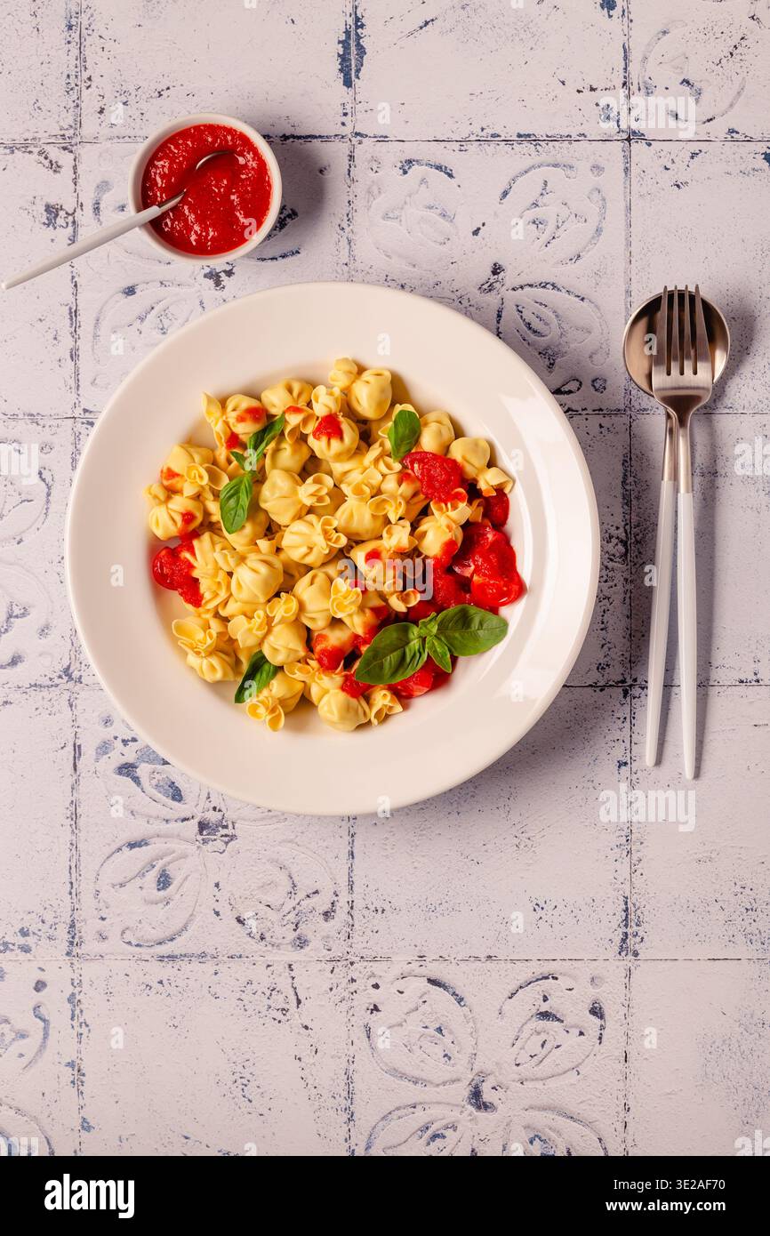 Pasta ripiena italiana. Sacсhettini pasta in un piatto con salsa di pomodoro. Foto Stock