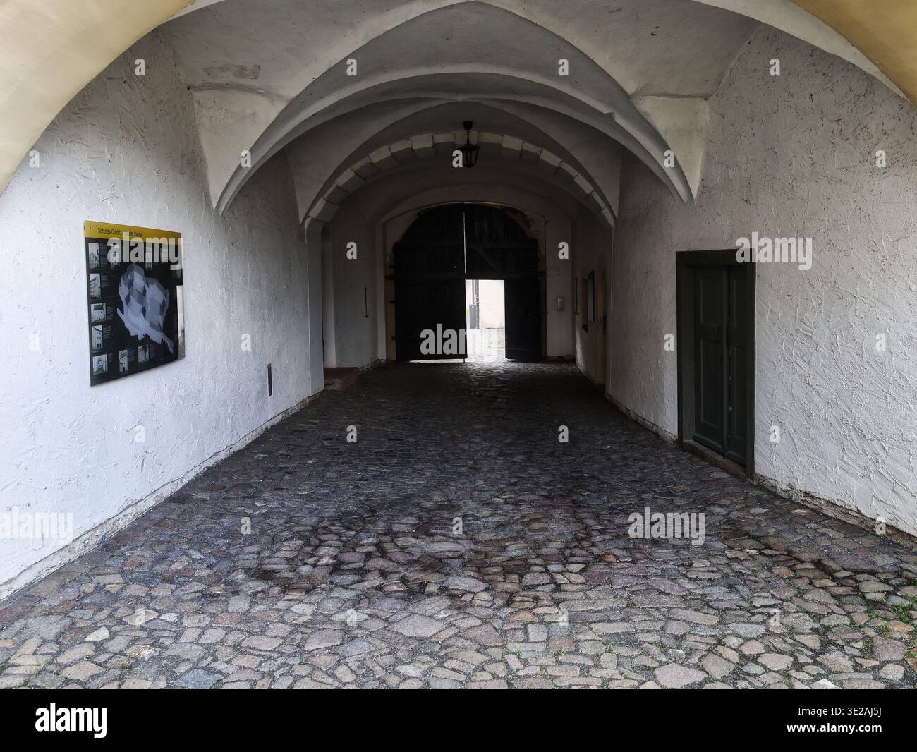 Castello di Colditz: Storica volta a crociera nella porta d'ingresso con vista sul massiccio cancello d'ingresso e bacheca informativa nell'ex campo Oflag IV-C. Foto Stock