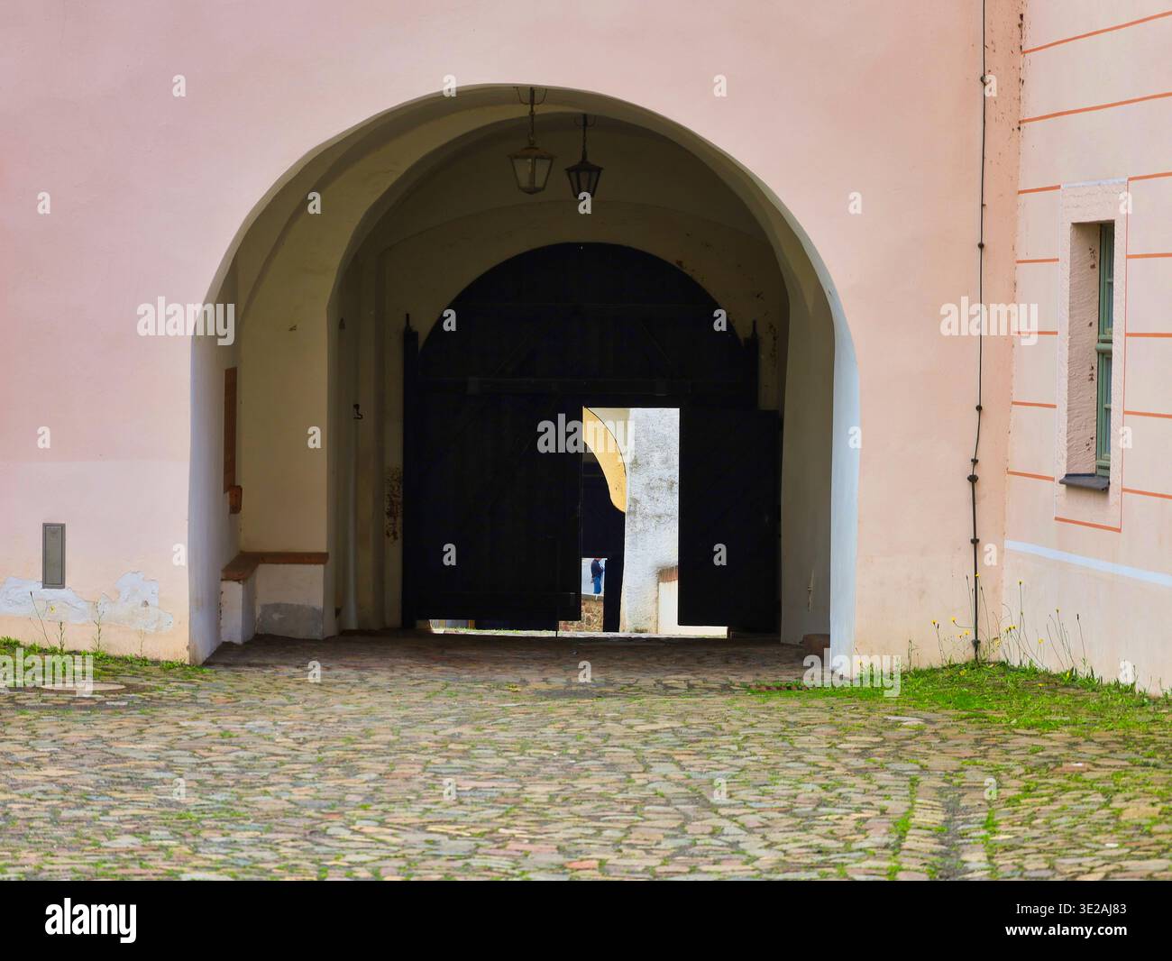 Castello di Colditz: Massiccio cancello in legno nero in un passaggio ad arco con vista sul luminoso cortile della storica fortezza sassone Foto Stock