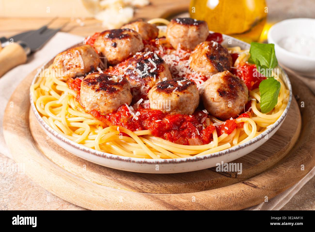 Un piatto di spaghetti classici conditi con polpette dorate e ricca salsa di pomodoro su un piatto di ceramica leggera. Foto Stock