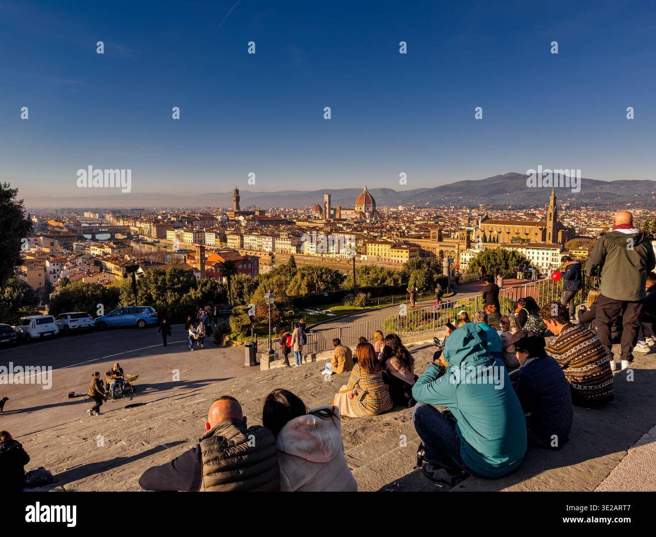 Persone sedute sulle scale ammirando la vista di Firenze da Piazzale Michelangelo, un famoso punto panoramico collinare a Firenze, in Italia Foto Stock