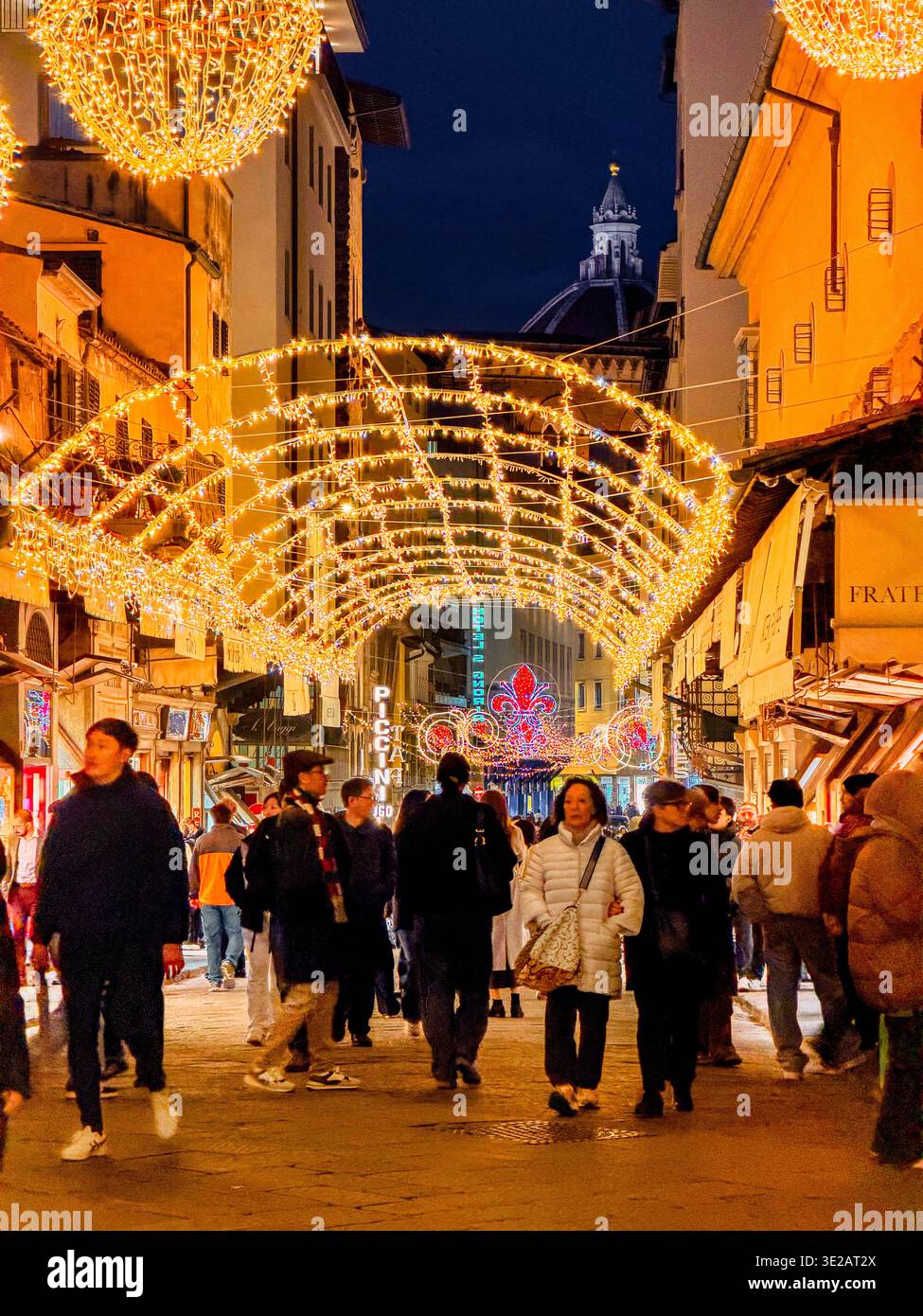 Periodo natalizio a Firenze con persone che camminano sotto le luci e le decorazioni natalizie sul Ponte Vecchio, a Firenze, Italia Foto Stock