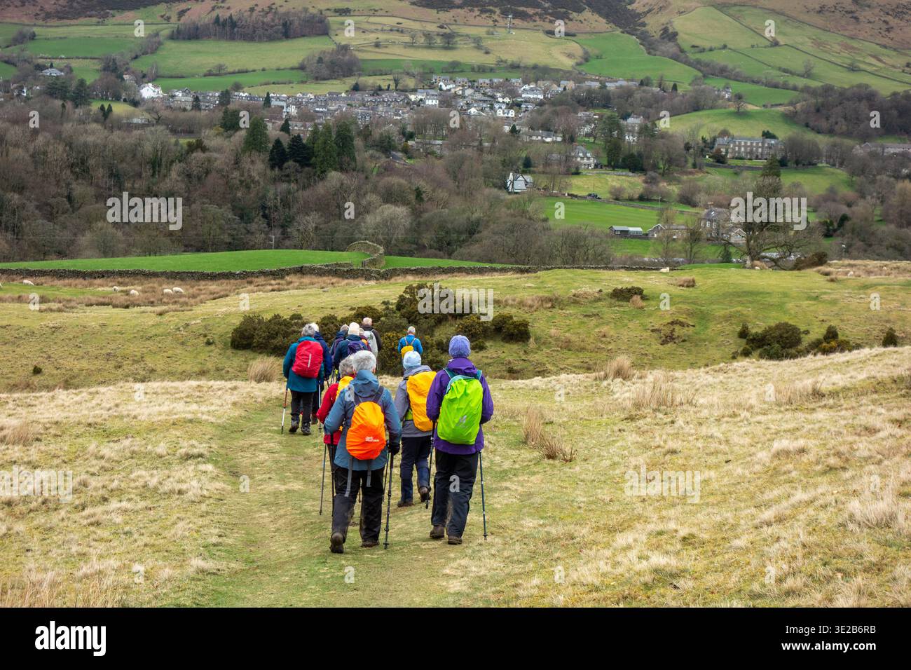 Gruppo di escursionisti che si arrampicano e fanno lo zaino in spalla lungo il sentiero di lunga distanza Dales Way che si avvicina al villaggio Cumbro di Sedbergh Foto Stock