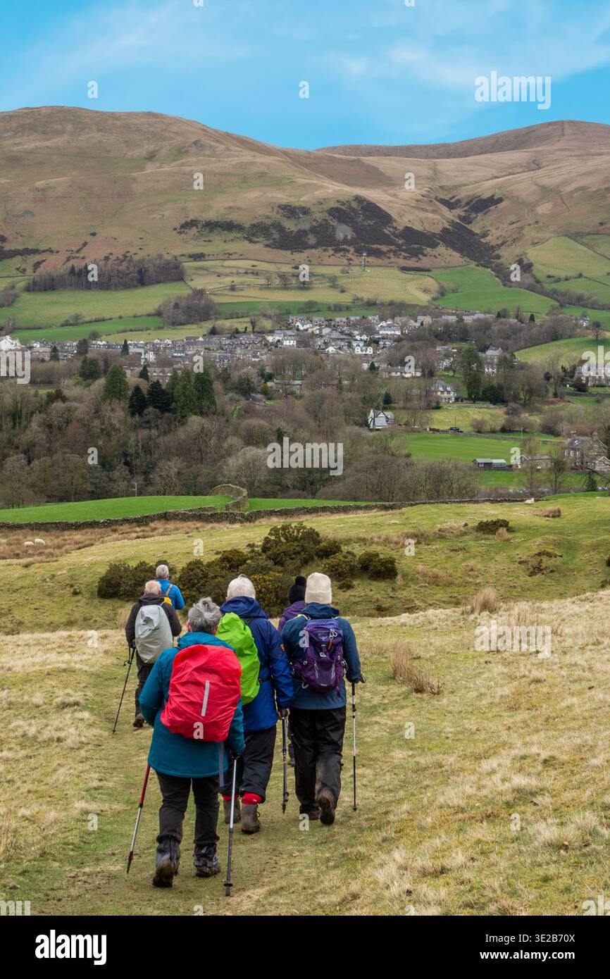 Gruppo di escursionisti che si arrampicano e fanno lo zaino in spalla lungo il sentiero di lunga distanza Dales Way che si avvicina al villaggio Cumbro di Sedbergh Foto Stock