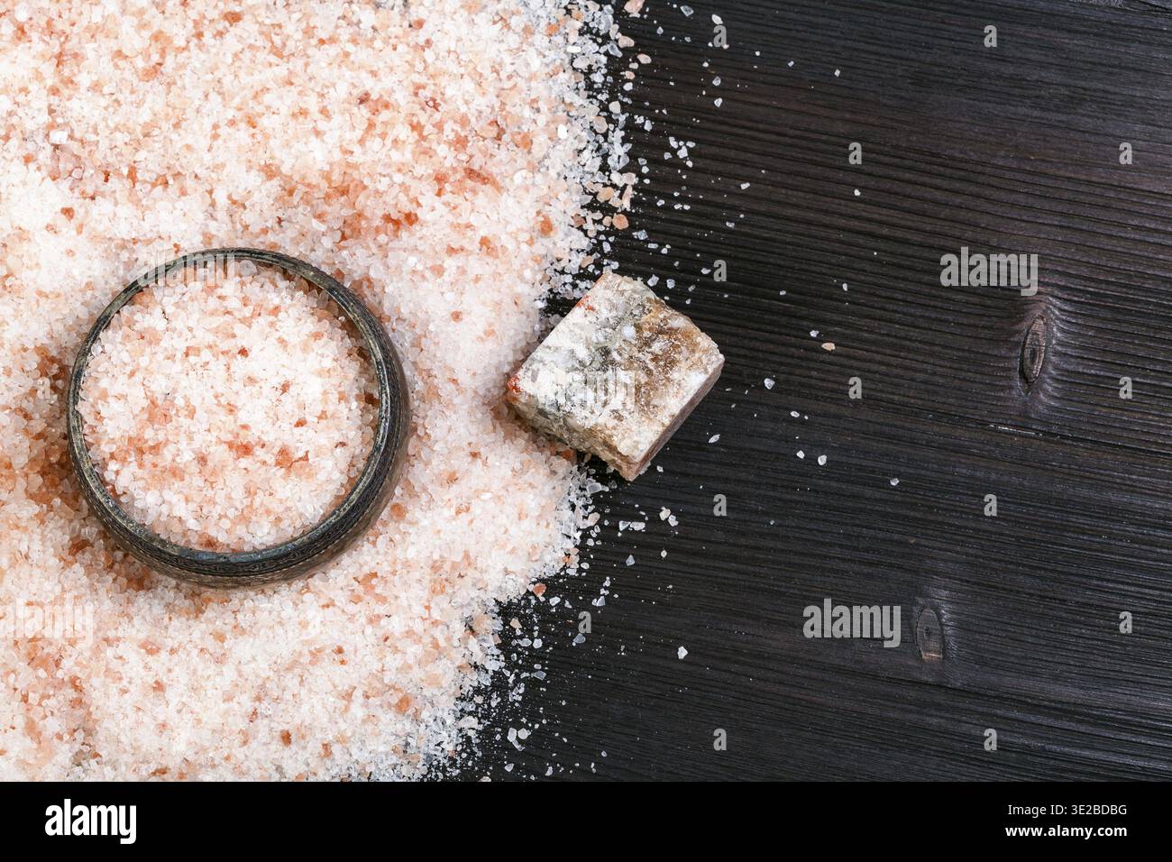 Vista dall'alto della cantina di sale d'argento, del minerale rozzo Halite rosa naturale e del sale himalayano granulare su tavola di legno marrone scuro Foto Stock