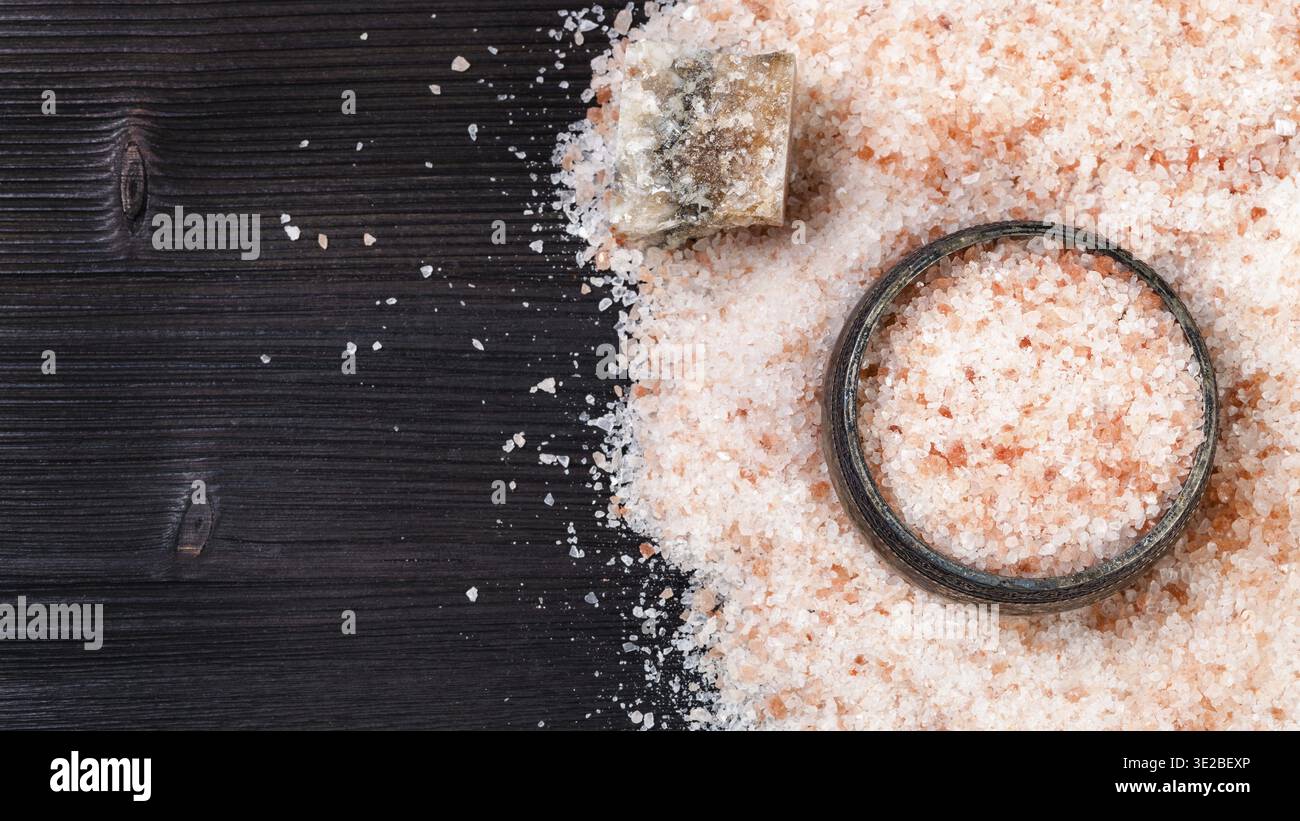 Vista dall'alto della cantina di sale d'argento, minerale Halite rosa naturale crudo e sale himalayano granulare su tavola di legno marrone scuro Foto Stock