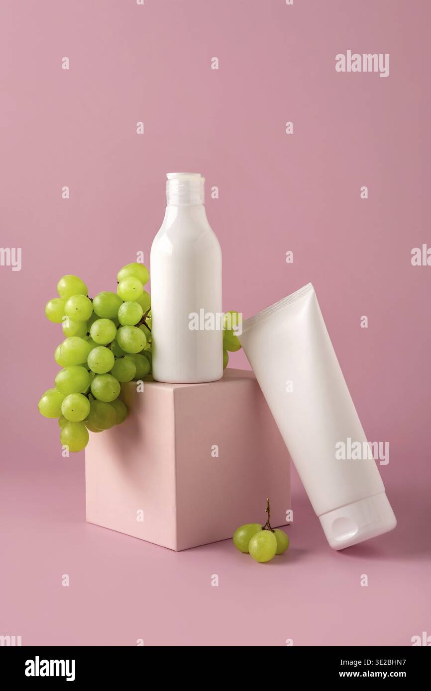 Bottiglia da mock-up per il branding con olio di semi d'uva sul podio. Set di confezioni per cosmetici. Prodotto cosmetico per la cura della pelle. Mock-up cosmetico su sfondo rosa Foto Stock