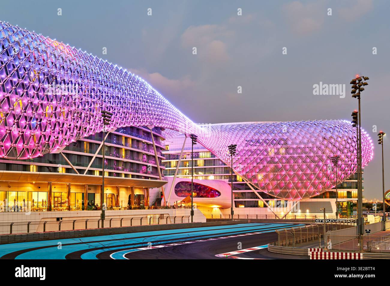 L'hotel W Abu Dhabi mostra luci accese di sera. La gente si gode la vivace scena intorno alla famosa struttura sull'Isola Yas. Foto Stock