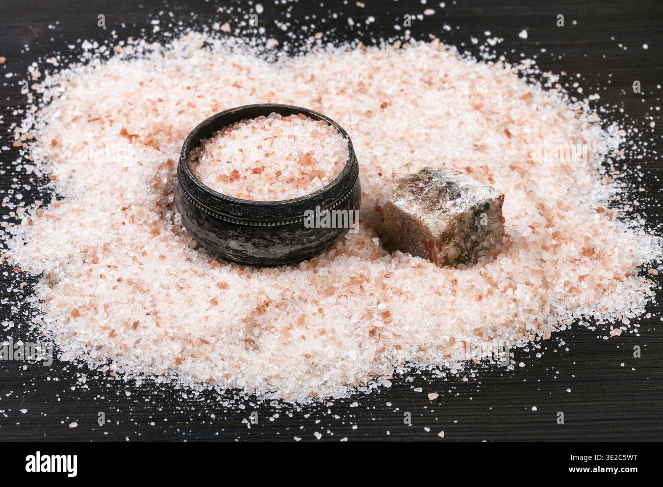 Antica cantina di sale d'argento, minerale naturale di Halite rosa crudo e sale himalayano granulare su tavola di legno marrone scuro Foto Stock