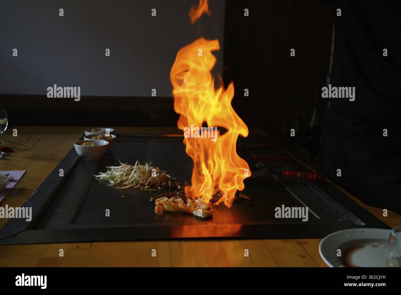 Le mani dello chef con la spatola sopra il teppanyaki. cucinare verdure, carne e pesce su un tavolo caldo per grigliate hibachi. Giapponese tradizionale. Spettacolo Teppan. cucina Foto Stock