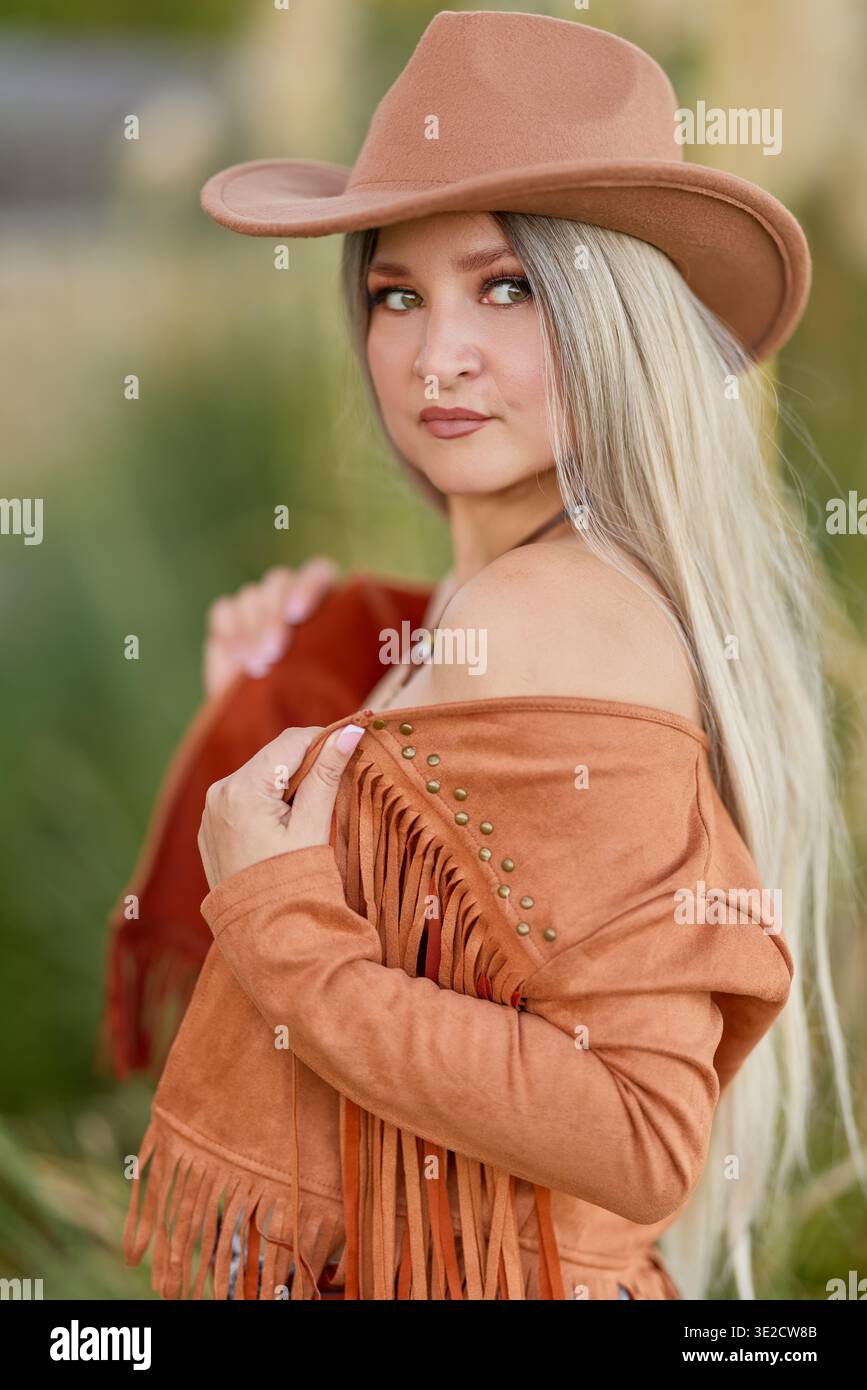 Ritratto all'aperto di una donna adulta che indossa un cappello e una maglietta a maniche lunghe, su un morbido sfondo sfocato in luce naturale. Foto Stock