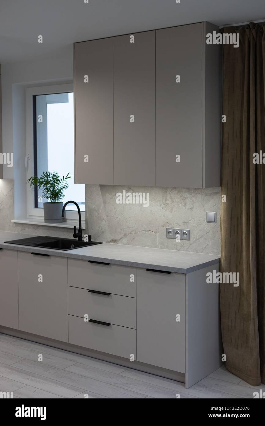 Gli eleganti interni contemporanei della cucina combinano armadi grigi, marmi splash e accenti neri per una sofisticata tavolozza di colori Foto Stock