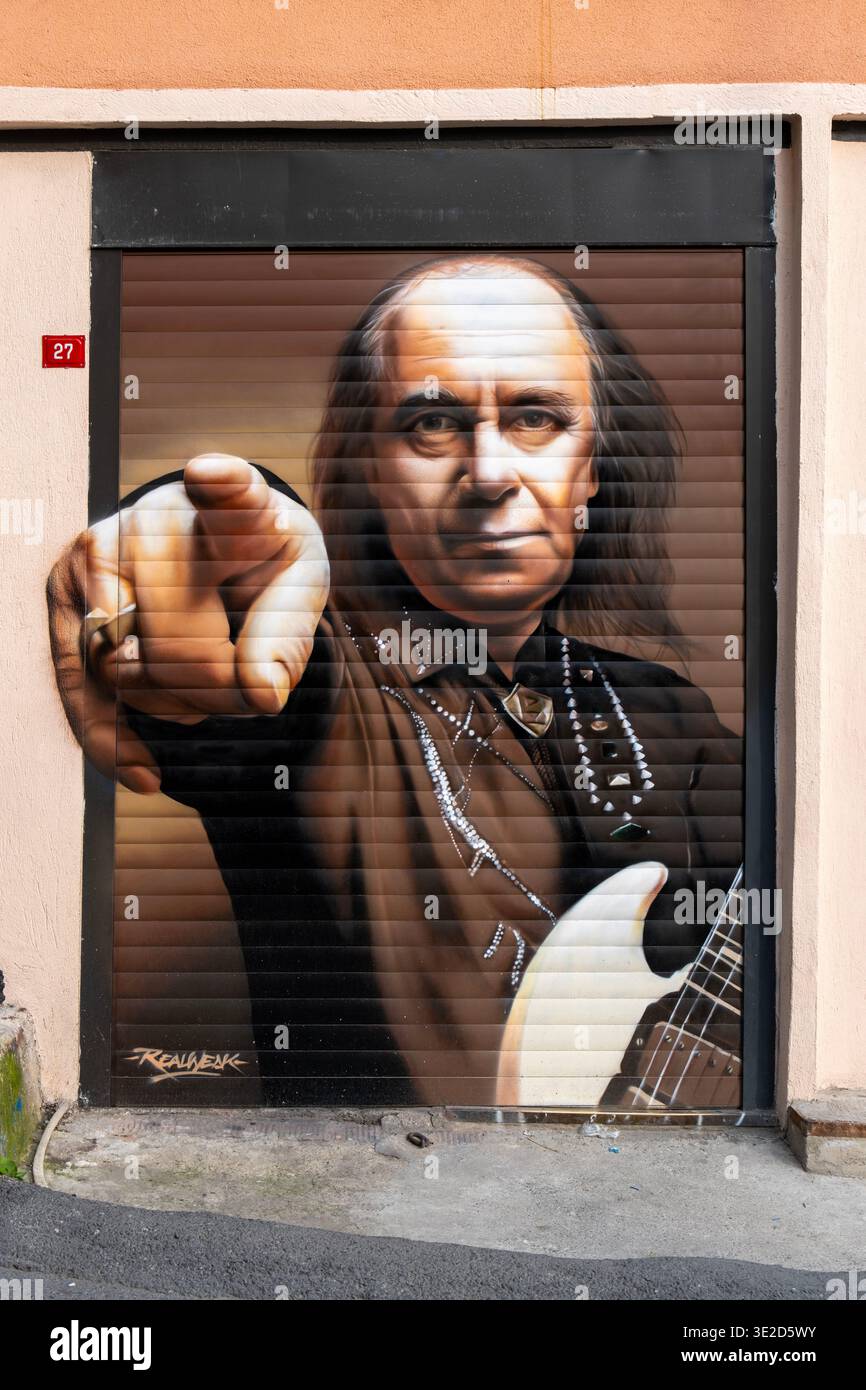 Audace murale fotorealistico di Street art di un uomo che punta allo spettatore con una chitarra elettrica su un garage chiuso Foto Stock