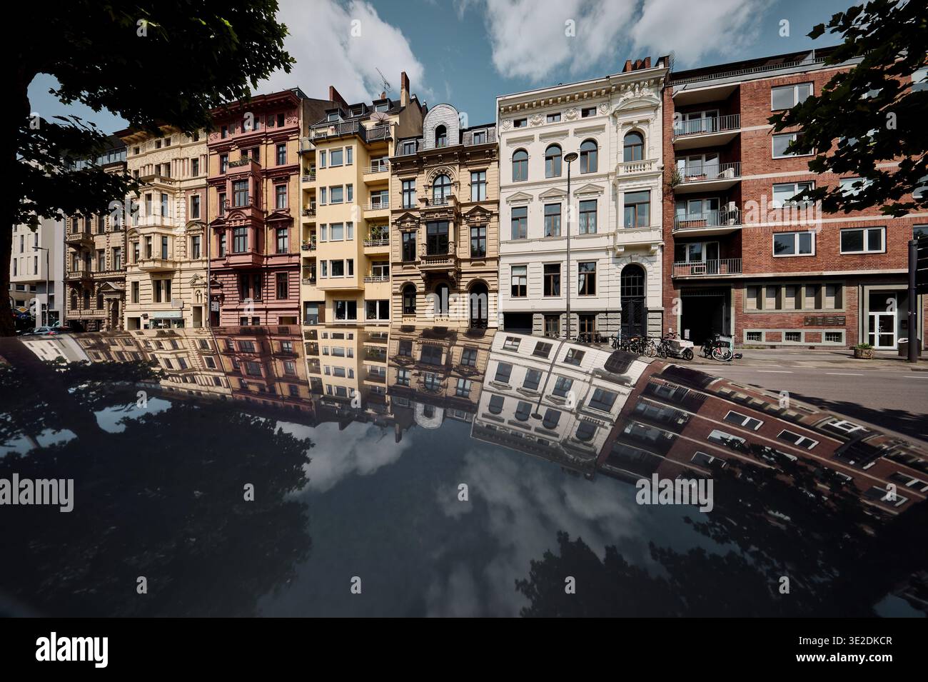 Foto creativa delle facciate colorate degli edifici storici di Hansaring, Colonia, che si riflettono sul tetto di un'auto lucida. Architettura urbana e scena di strada. Foto Stock
