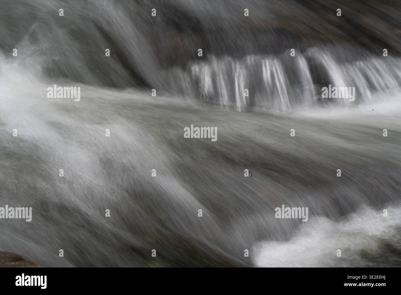 Un flusso d'acqua scorre attraverso un'area rocciosa. La scena è tranquilla e serena. Foto Stock