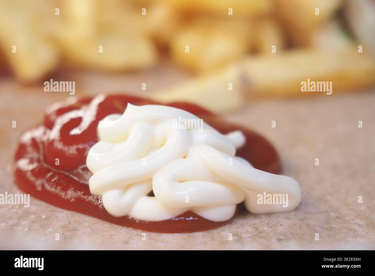Ketchup e maionese posizionati accanto alle patatine fritte su un tavolo Foto Stock