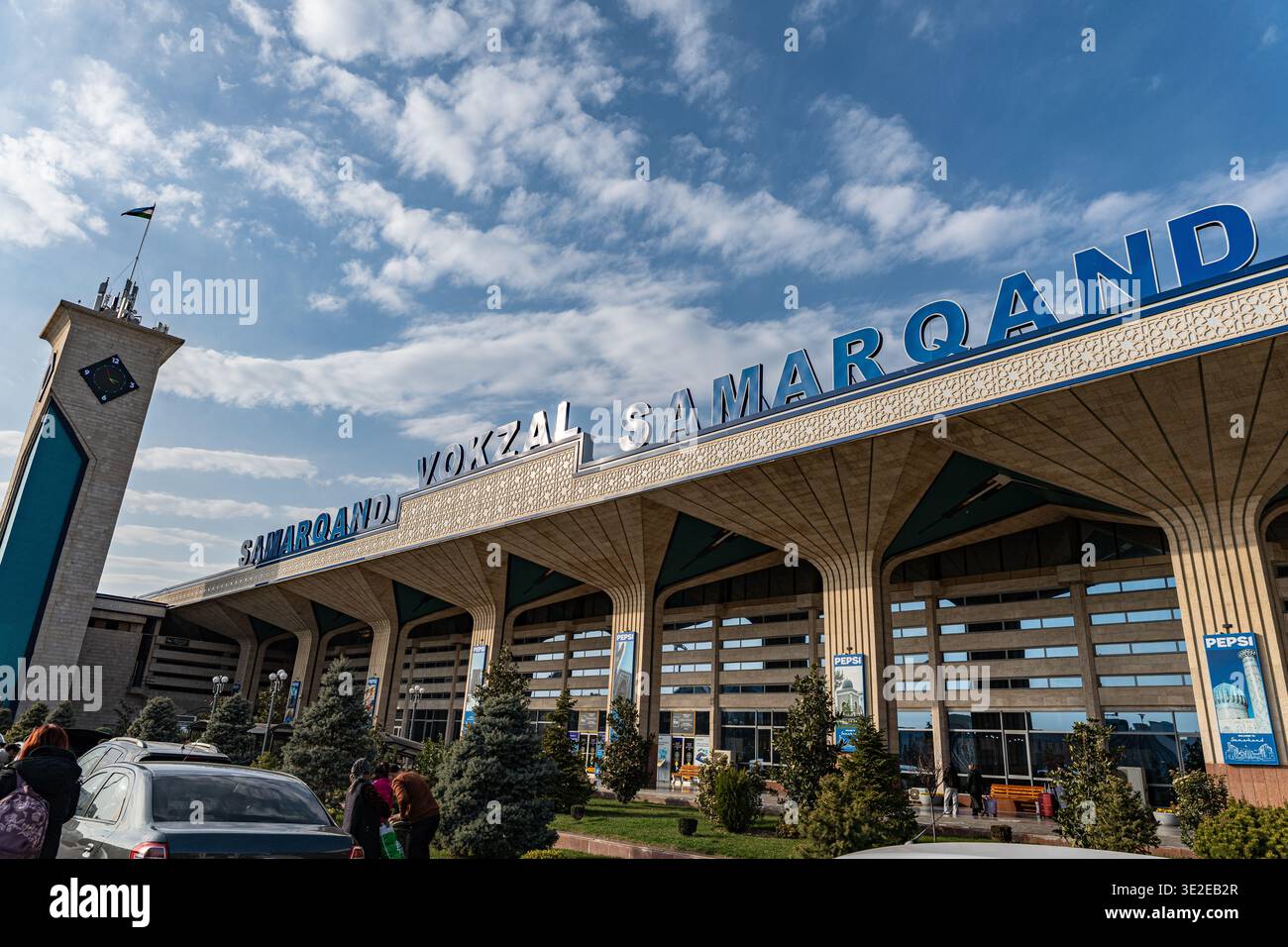 1 MARZO 2026 - Samarcanda, Uzbekistan: L'impressionante esterno della stazione ferroviaria di Samarqand presenta un'architettura moderna e un cielo vibrante. Foto Stock