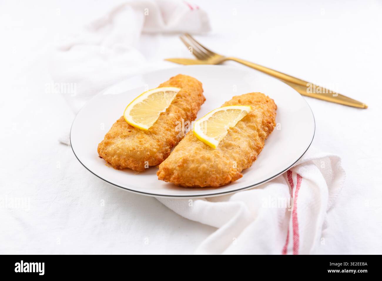 Filetti di pesce gatto fritti croccanti serviti con fette di limone Foto Stock