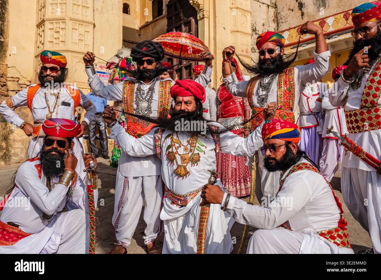 Uomini con baffi eccezionalmente lunghi e turbanti colorati posano con spade al festival Bundi Utsav fuori da una porta decorata. Foto Stock