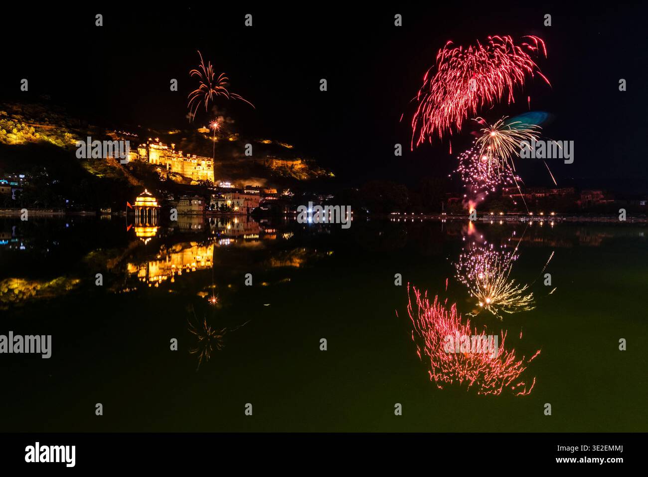 I fuochi d'artificio illuminano il cielo notturno sul lago Nawal Sagar a Bundi, con il Palazzo Garh illuminato che si riflette nelle acque calme. Foto Stock