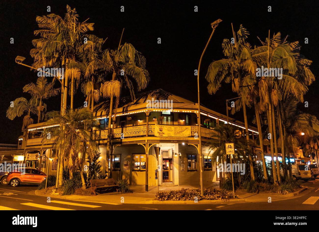 Accogliente pub in un angolo di notte, palme tropicali e luci calde creano un'atmosfera invitante. Foto Stock