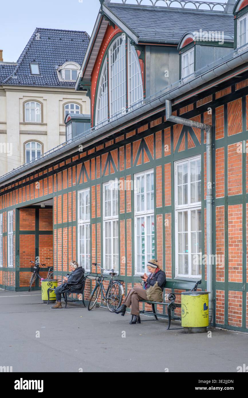 Seduti sulle panchine e usando i telefoni cellulari alla stazione ferroviaria di Osterport, Copenhagen Foto Stock