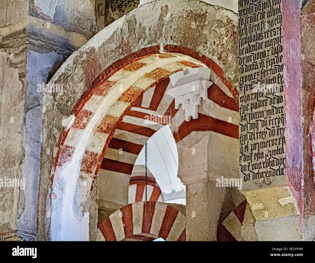 Una sezione del tetto della Mezquita a Cordova con gli antichi archi islamici in contrasto con una porzione di testo latino dell'influenza cattolica. Foto Stock