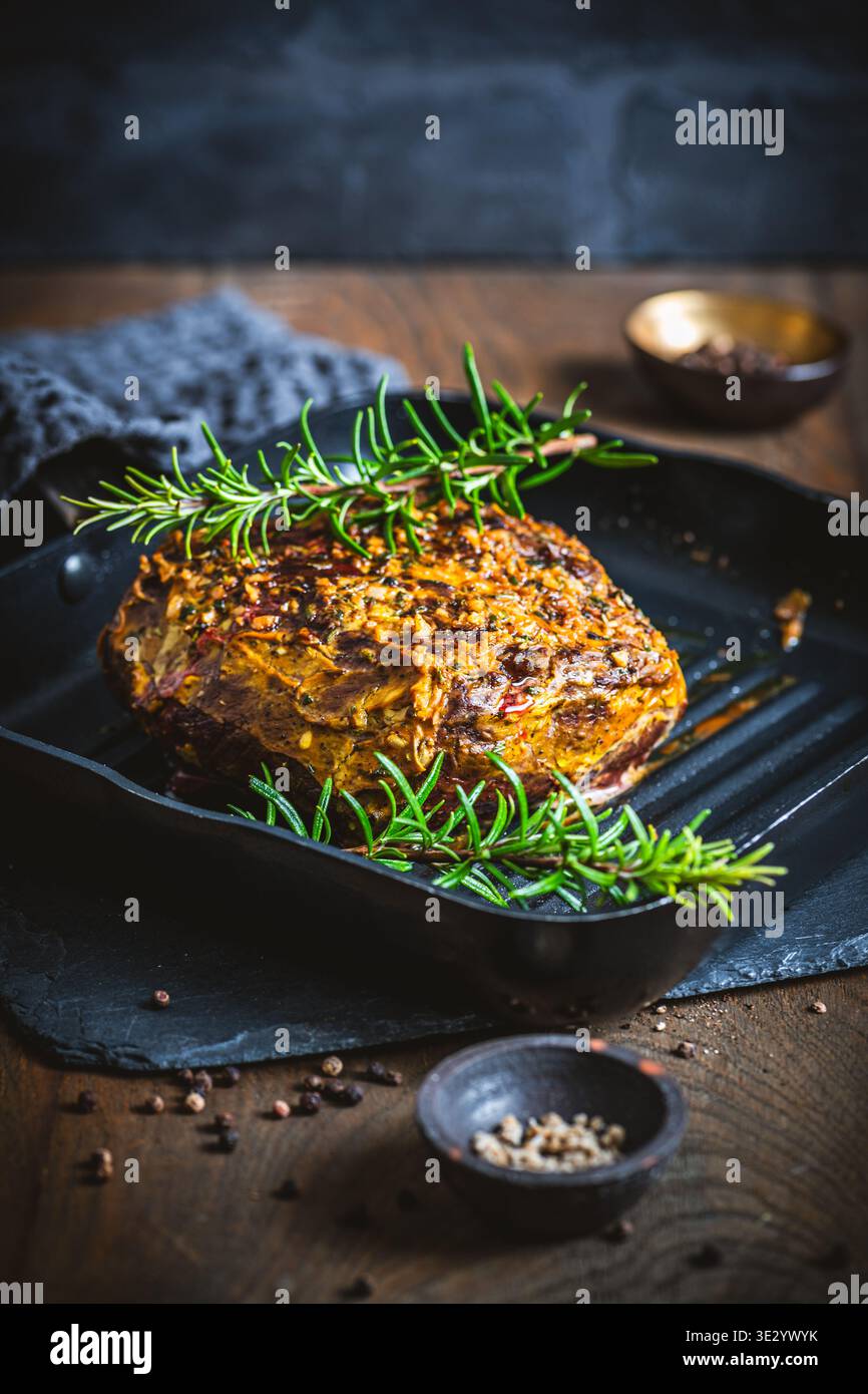 Arrosto di manzo in un pezzo, servito con una crosta di senape-erbe, fresco dal forno, su un rustico tavolo di legno, verticale Foto Stock