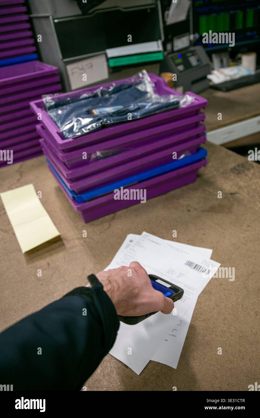 Operatività del magazzino utilizzando uno scanner portatile per leggere un codice a barre su documenti di prelievo o spedizione in un magazzino di e-commerce o in un centro di distribuzione Foto Stock