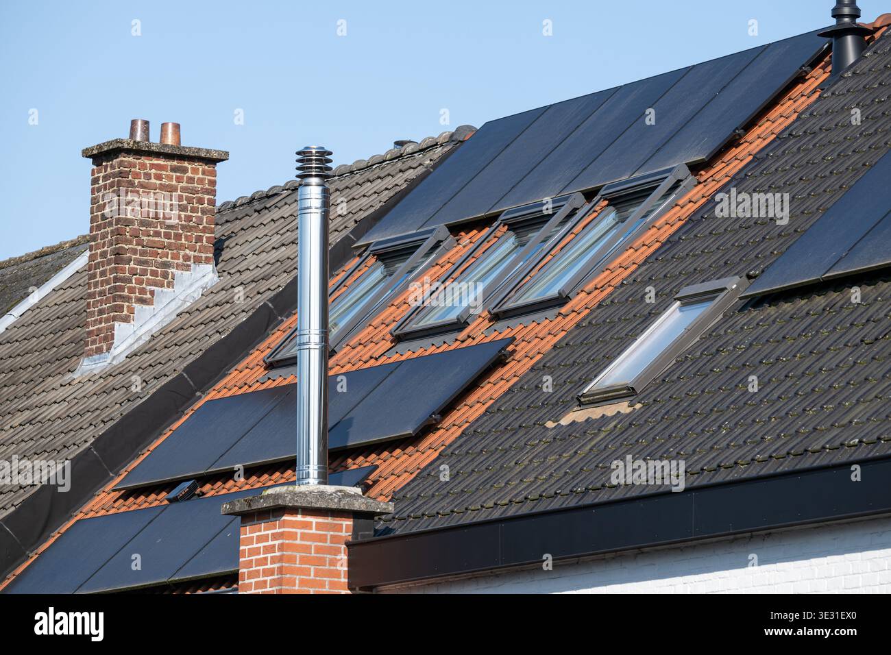 Pannelli solari installati su un tetto recentemente rinnovato con camino, riflettendo le attuali tendenze in materia di efficienza energetica, isolamento e sostenibilità ambientale Foto Stock