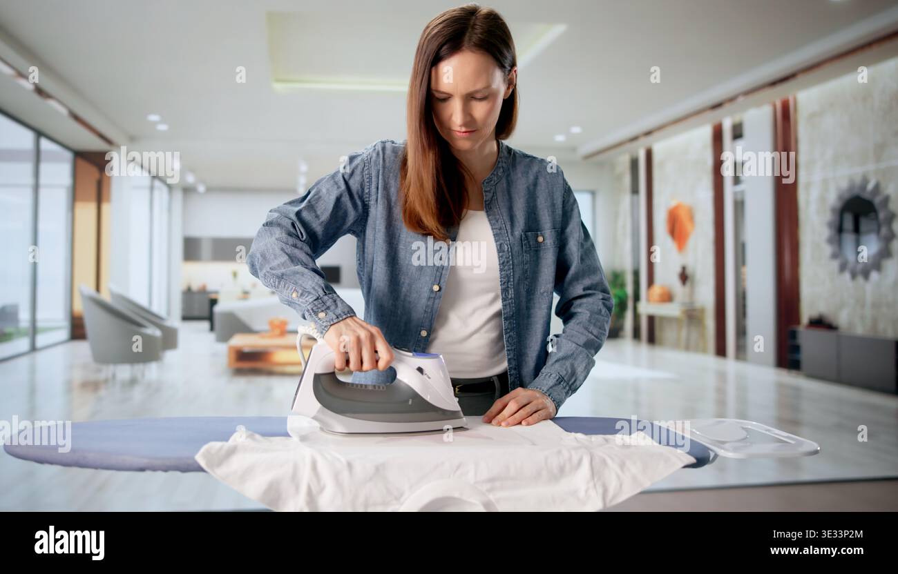 Donna che prema il design personalizzato a trasferimento di calore su una T-shirt a casa Foto Stock