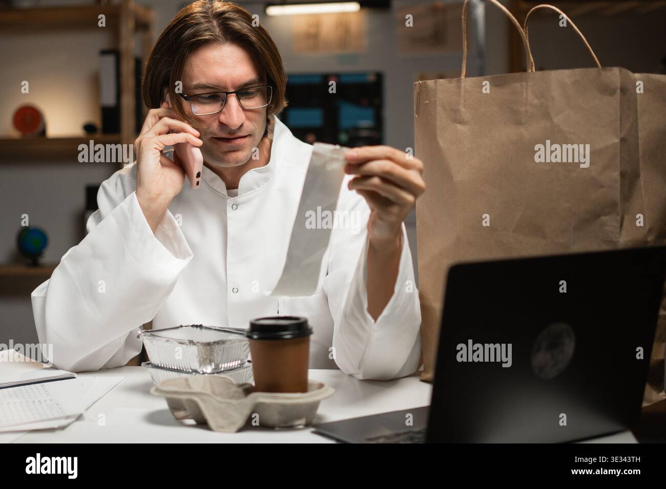 maschio medico disimballaggio cibo da asporto lettura ricetta ristorante in ospedale mentre si lavora sul turno di notte. Concetto di consumo, medicina, cibo e peo Foto Stock