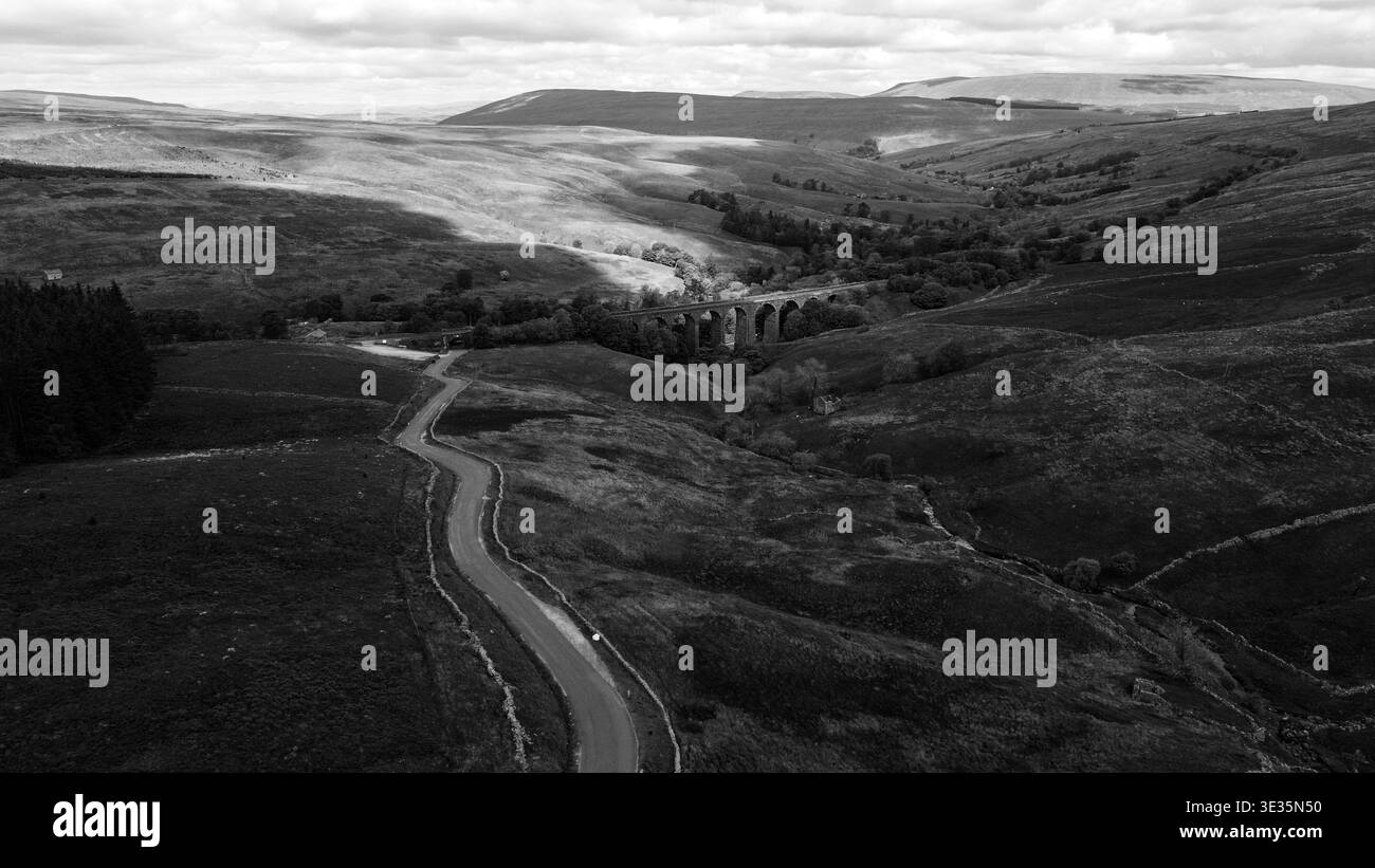 Vista monotona sopraelevata del Dent Head Viaduct e di una strada tortuosa annidata nella valle delle Dales dello Yorkshire Foto Stock