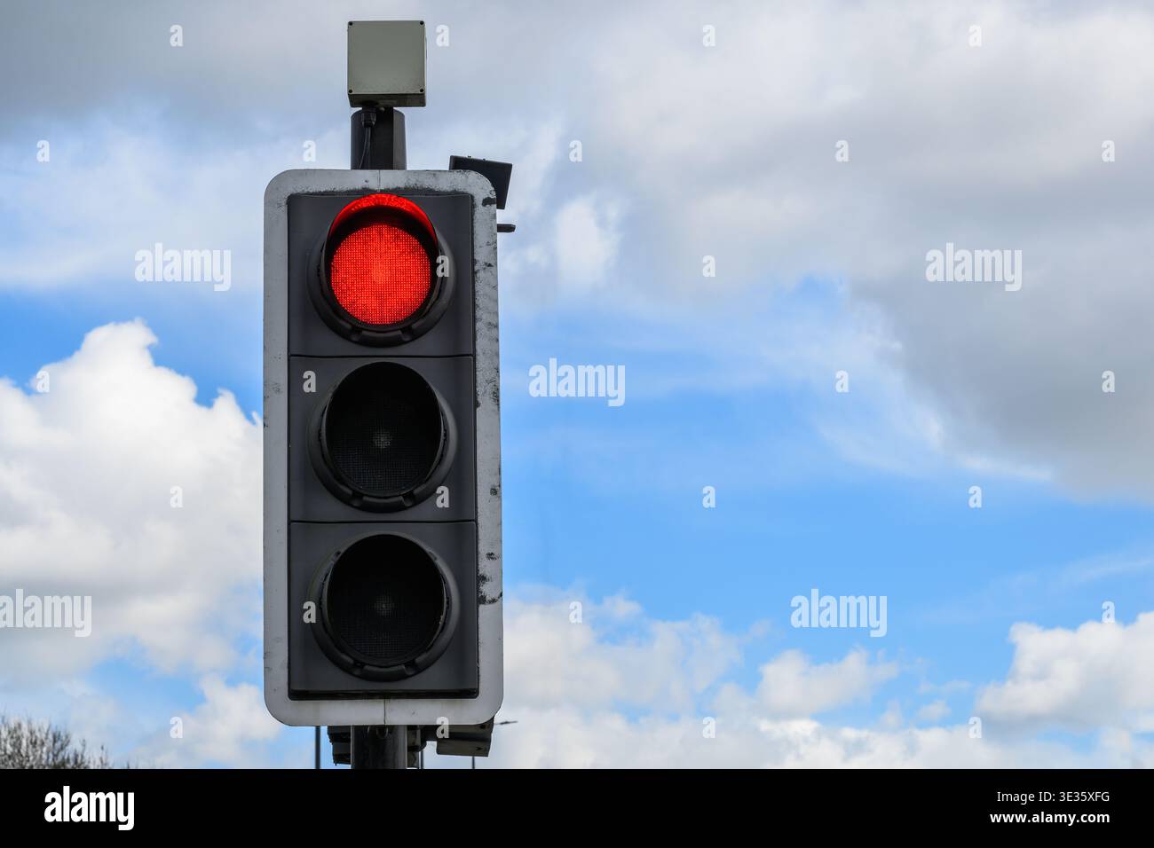 Primo piano del semaforo che mostra un segnale rosso contro il cielo azzurro, simboleggia lo stop, la sicurezza stradale e il controllo del trasporto urbano. Foto Stock