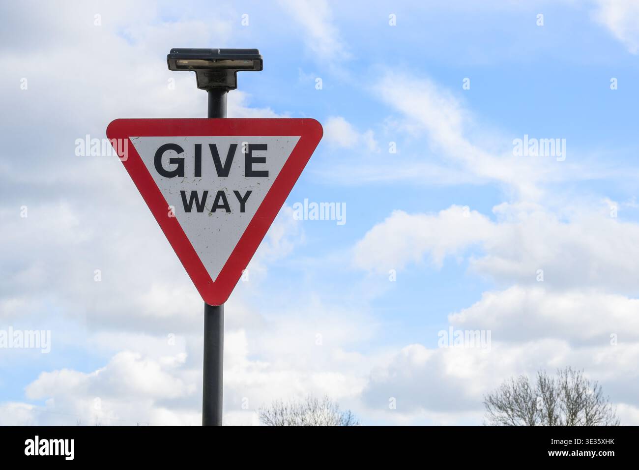 Primo piano di un segnale stradale triangolare del Regno Unito contro un cielo limpido, che simboleggia le regole del traffico, la sicurezza e la navigazione stradale. Foto Stock